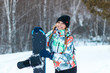 © Марина Демешко - Beautiful positive blond girl in pigtails in colorful jacket with snowboard is smiling, standing on top of the mountain. Winter sunny day