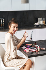 Sticker - Image of caucasian young beautiful woman applying face makeup at home