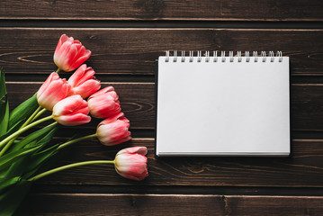 Wall Mural - pink flowers tulips with blank Notepad on wooden table for greeting card