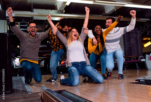 Fotomural Group of friends enjoying time together laughing and cheering while bowling at club