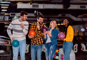 Wall Mural - Group of friends enjoying time together laughing and cheering while bowling at club.