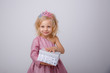 © Olesya Pogosskaya - cute little girl in a princess dress with a crown holding a gift on a white background