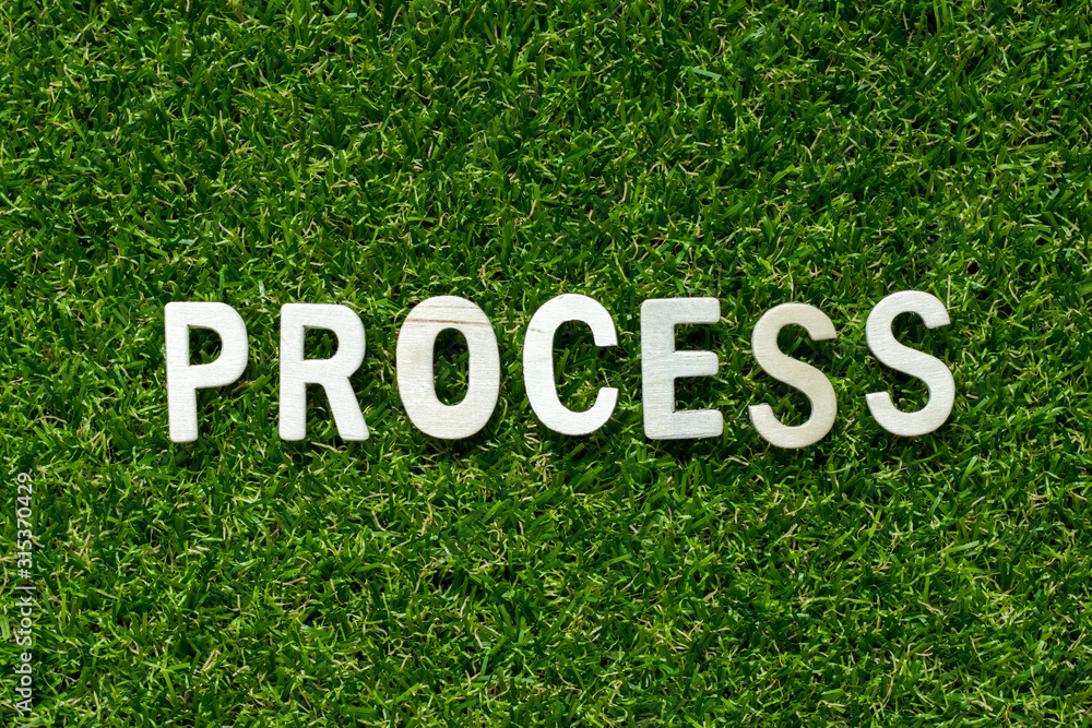 Wood alphabet in word process on artificial green grass background ...