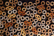 Bublik cookies pattern. Ring shaped roll cookies with different glaze on dark background..
