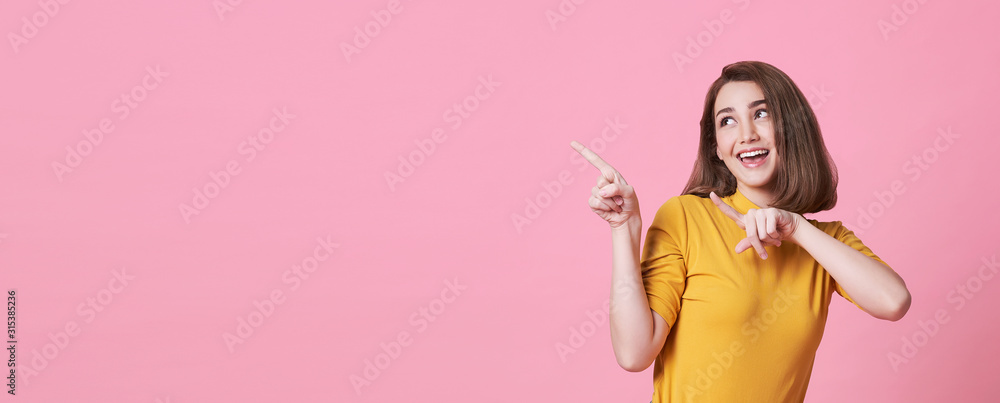 Beautiful healthy young woman smiling with his finger pointing and looking at on light pink banner background with copy space. - obrazy, fototapety, plakaty 