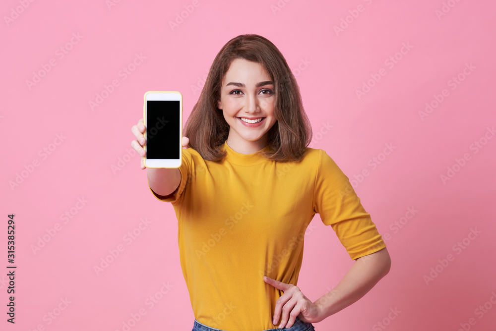 Portrait of happy young woman showing at blank screen mobile phone isolated over pink background. - obrazy, fototapety, plakaty 