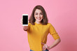 © NaMong Productions - Portrait of happy young woman showing at blank screen mobile phone isolated over pink background.