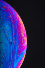Wall Mural - close up macro photograph of the psychedelic rainbow of colors mixing and swirling in a soap bubble 