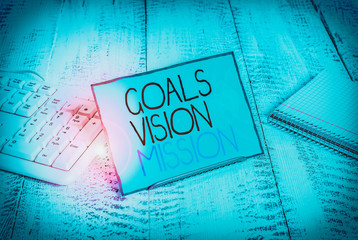 Writing note showing Goals Vision Mission. Business concept for practical planning process used to help community group Notepaper on wire in between computer keyboard and sheets