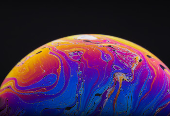 Wall Mural - close up macro photograph of the psychedelic rainbow of colors mixing and swirling in a soap bubble 