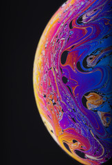 Wall Mural - close up macro photograph of the psychedelic rainbow of colors mixing and swirling in a soap bubble 