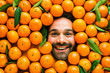 © karepa - Man with ripe oranges, concept for food industry. Face of grimacing man in oranges or mandarins area
