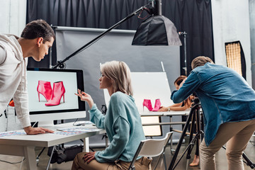 attractive art director gesturing near computer monitor with photo of shoes