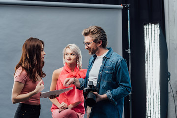 attractive art director looking at photographer near beautiful model