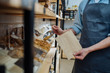 © Iryna - Mixed race male worker shop assistant filling paper bag with oat granola in bulk products in dispensers and food available at zero waste shop.