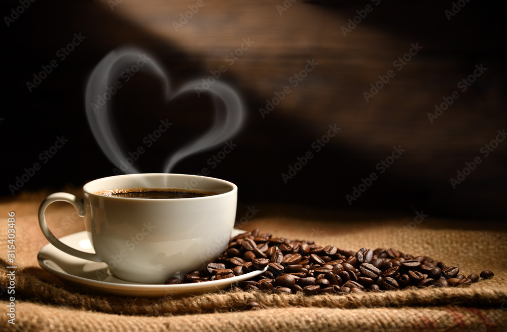 Cup of coffee with heart shape smoke and coffee beans on burlap sack on old wooden background - obrazy, fototapety, plakaty 