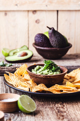 Wall Mural - Mexican traditional food, guacamole sauce, ingredients  avocado, cilantro, lime and tortilla corn chips