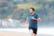 © Egoitz Bengoetxea/ADDICTIVE STOCK - Bearded male athlete in active wear running during empty sandy beach with green mountains on blurred background