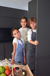 © PHILIPPE DEGROOTE/ADDICTIVE STOCK - Little funny male and female kids in aprons having fun while searching ingredients in closet and looking at camera at modern kitchen