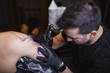© Raquel Arocena/ADDICTIVE STOCK - Master doing tattoo on forearm of male customer