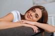 © LIGHTFIELD STUDIOS - happy young woman looking at camera while relaxing on sofa in living room