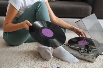 Wall Mural - cropped view of tattooed girl sitting on carpet and touching vinyl record near retro record player