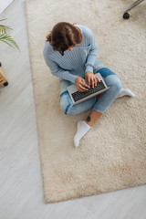 Wall Mural - top view of blogger using laptop while sitting on carpet