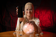Fortune Teller With Crystal Ball And Mobile Phone On Table With Candles. Smartphone, Online Or Call Concept