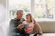 © Westend61 - Happy senior couple relaxing on couch at home using tablet for online shopping
