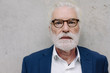 © Westend61 - Portrait of serious senior businessman at a concrete wall