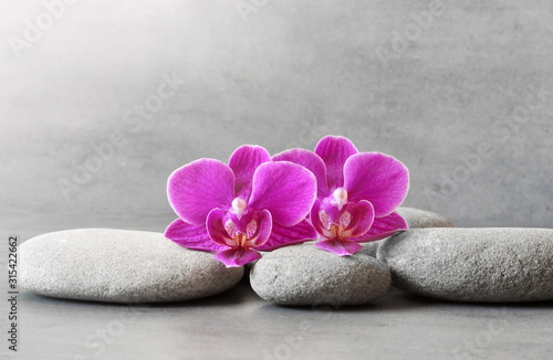 Dekoracja na wymiar  kamienie-spa-i-kwiat-orchidei-na-szarym-tle