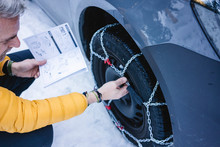Man putting the snow chains on his car