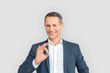 © Viktoriia - Freestyle. Mature businessman standing isolated on white showing ok gesture winking to camera playful