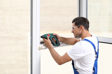 Poster - Construction worker repairing plastic window with electric screwdriver indoors