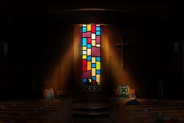 Touched by The Light.  Two Church goers are lit by a beam of light from the churches stained glass windows.  