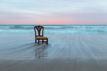 Old chair on the ocean coast, dramatic sky, melancholic scene, loneliness, long exposure