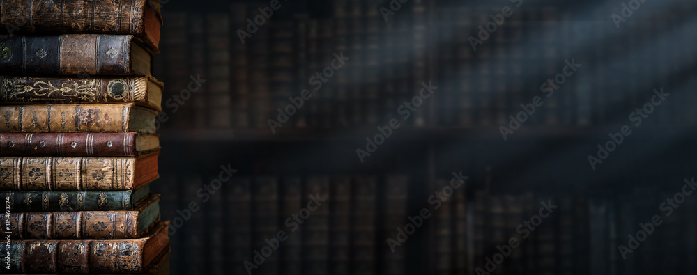 Old books on wooden shelf and ray of light. Bookshelf history theme grunge background. Concept on the theme of history, nostalgia, old age. Retro style. - obrazy, fototapety, plakaty 
