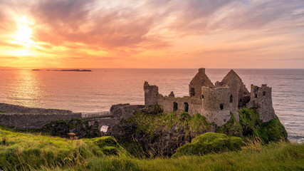 Ruined medieval Dunluce Castle on the cliff at amazing sunset, Wild Atlantic Way, Bushmills, County Antrim, Northern Ireland. Filming location of popular TV show, Game of Thrones, Castle Greyjoy