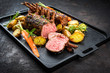 © HLPhoto - Barbecue rack of lamb with carrot and potatoes offered as closeup on a modern design cast iron tray
