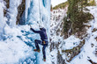 © XtravaganT - Ice Climbing Man with an Ice Axe and Crampons on a Frozen Waterfall