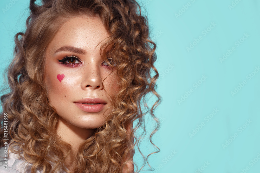 Pretty girl with curls hairstyle, classic makeup, freckles, nude lips and manicure design with hearts. Beauty face. The image for Valentine's Day - obrazy, fototapety, plakaty 