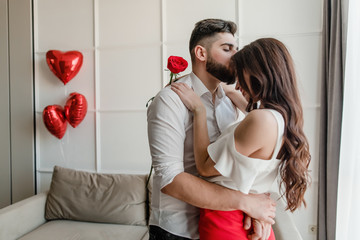 Wall Mural - couple man and woman in love with red rose and heart shaped balloons at home