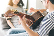 © panitan - couple playing acoustic guitar,sing folk song together sitting on sofa at home.concept for happy moments of young lovers,family.music and art therapy for people with stress.asian man,women relax time