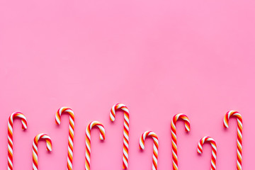 Christmas candies frame - cane with red and white stripes - on pink background top-down copy space