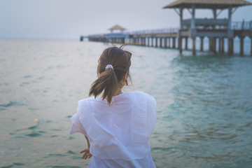 An Asian woman is smiling on the beach.