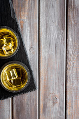 Scotch - two glasses with ice - on dark wooden background top-down frame copy space