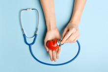 Female Hands With Red Heart And Stethoscope On Color Background. Cardiology Concept