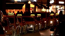 Row Of Taxi. Night Transportation In Urban City. Illuminated Scene After Dark. Downtown Munich Taxi Cars To Transport Tourist. Slow Motion Movement