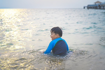 A boy is playing sand and swimming with his brother on the beach.