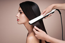 Hairdresser Straightening Long Dark Hair With Hair Irons. Beautiful Woman With Long Straight Hair. Smooth Hairstyle